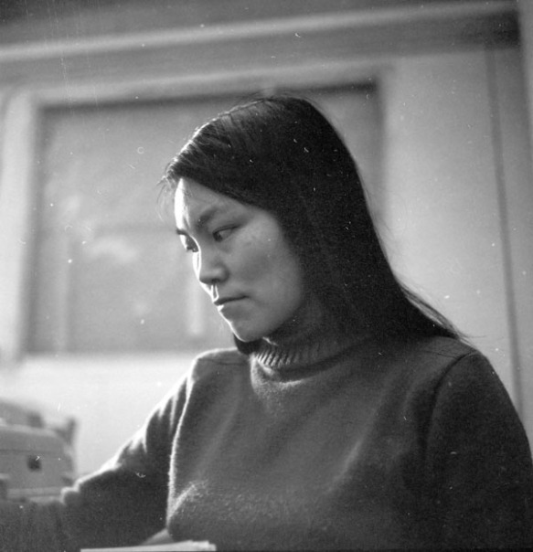 Photograph of a young Inuit woman wearing a turtle neck sweater looking away from the camera.