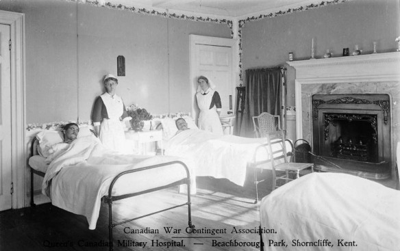 A black-and-white photograph showing two nursing sisters standing by the bedsides of two wounded men. 