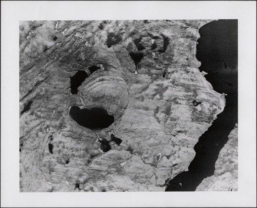 A black-and-white aerial photograph of a crater. The arc of a circle is visible in an area now consisting of lakes and hills.