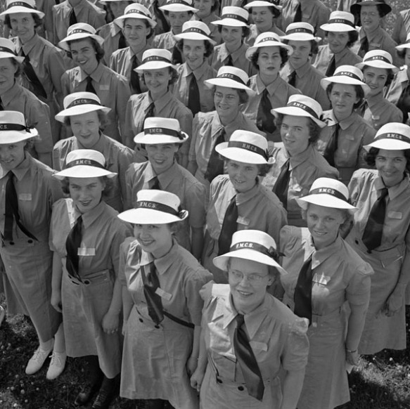 A black-and-white photograph of a crowd of smiling <abbr title=