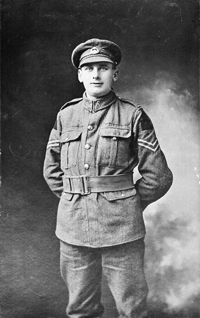 A black-and-white studio photograph of a soldier standing with his hands behind his back. 