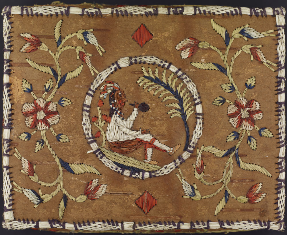 A birch bark basket embroidered in the centre with a First Nations figure smoking a pipe, and white, red, and blue flowers on each side.