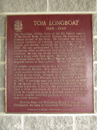 A red rectangle plaque with gold writing, with the crest of Canada and “Tom Longboat 1886–1949” at the top.
