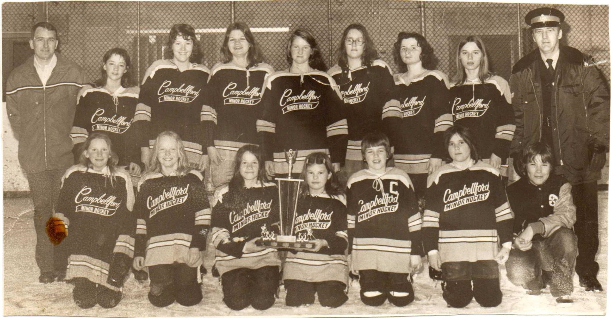 A sepia photo of a girls’ hockey team with Campbellford Minor Hockey written on their sweaters. 