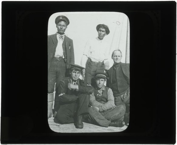 Group of five men standing or sitting.