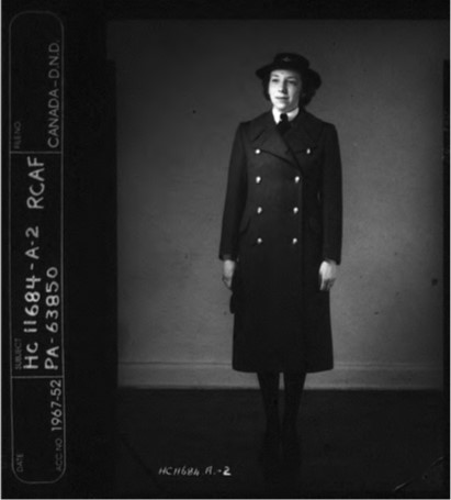 A uniformed woman stands against a blank wall.