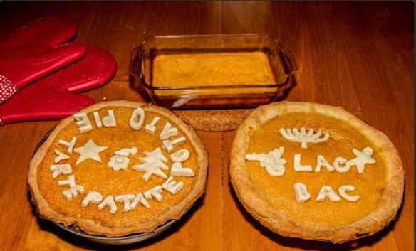 Image featuring two sweet potato pies with embellishments made from leftover crust mix; a sweet potato pudding; and a pair of red oven mitts.
